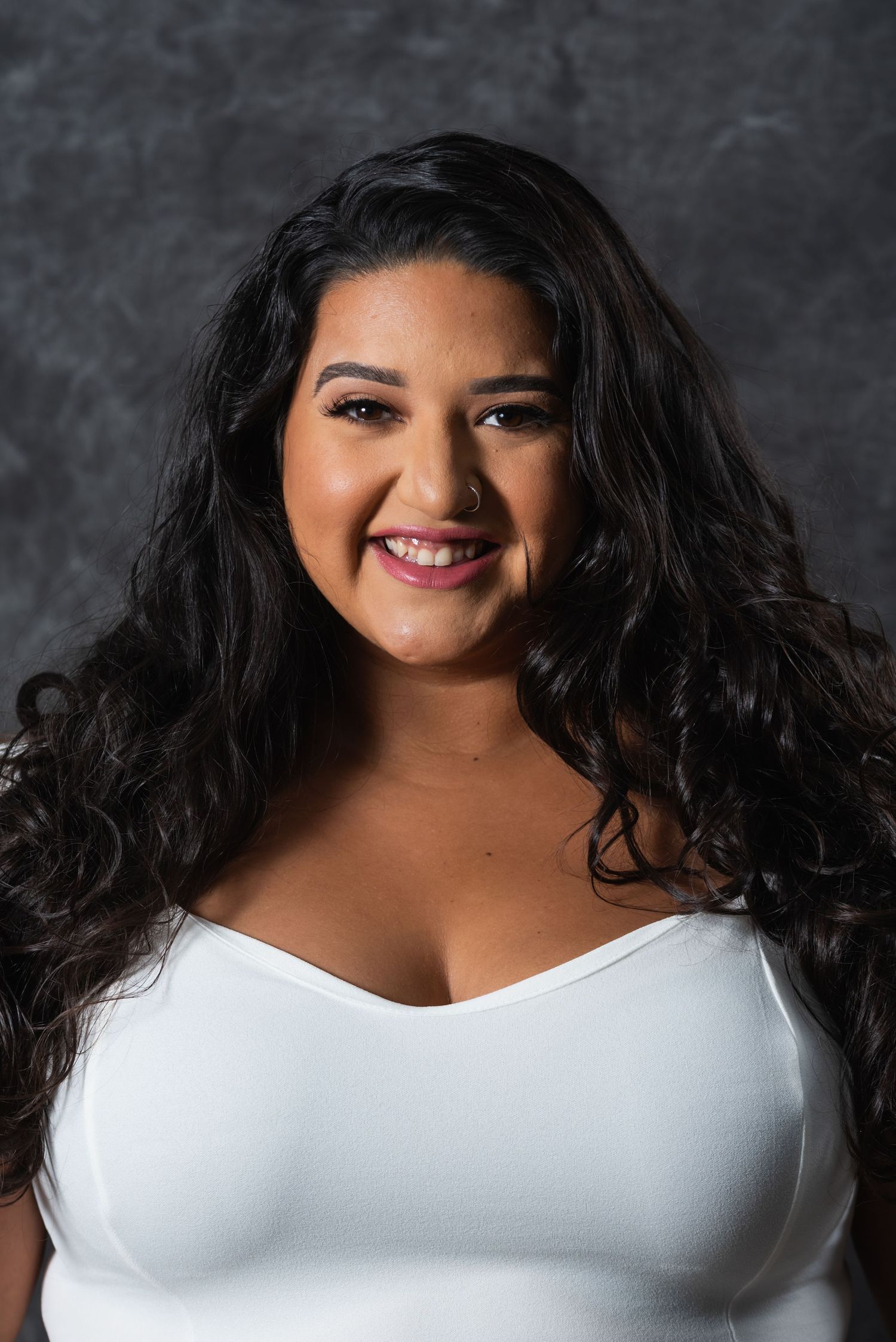 Studio portrait in white top showing natural, cheerful expression.