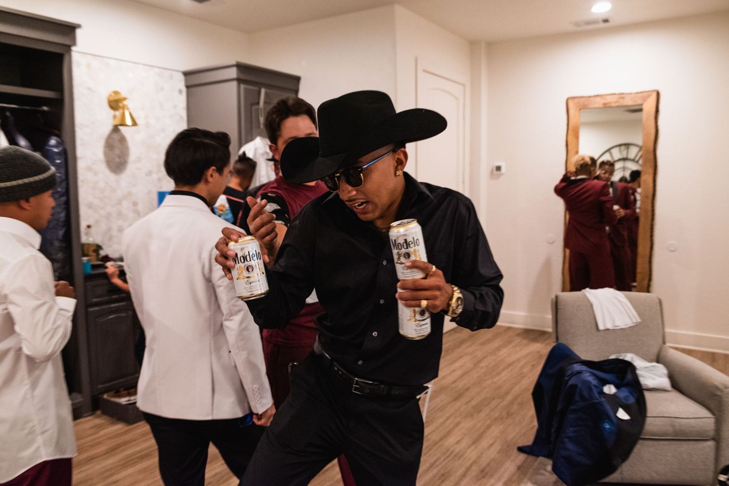 Group in formal attire and cowboy hats gathering in indoor venue setting.