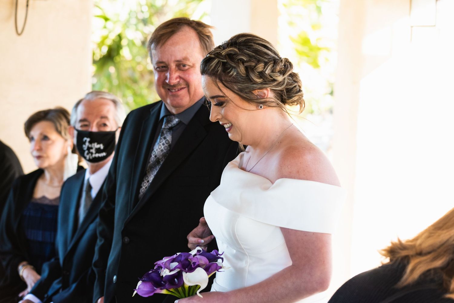 Emotional wedding moment captured during an outdoor ceremony with purple flowers.