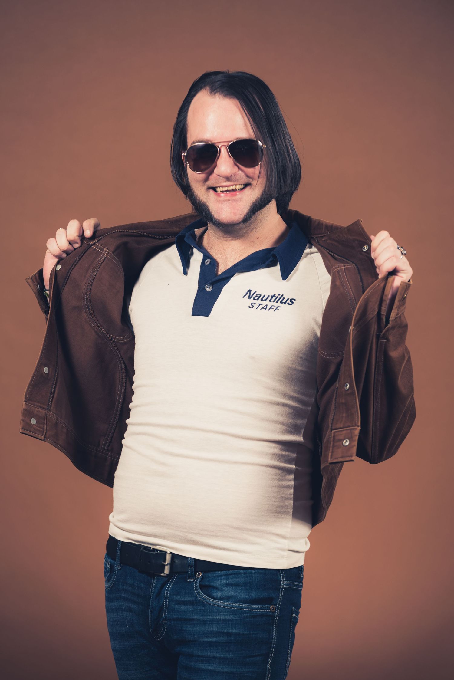Person in brown jacket showing off casual attire against studio background.