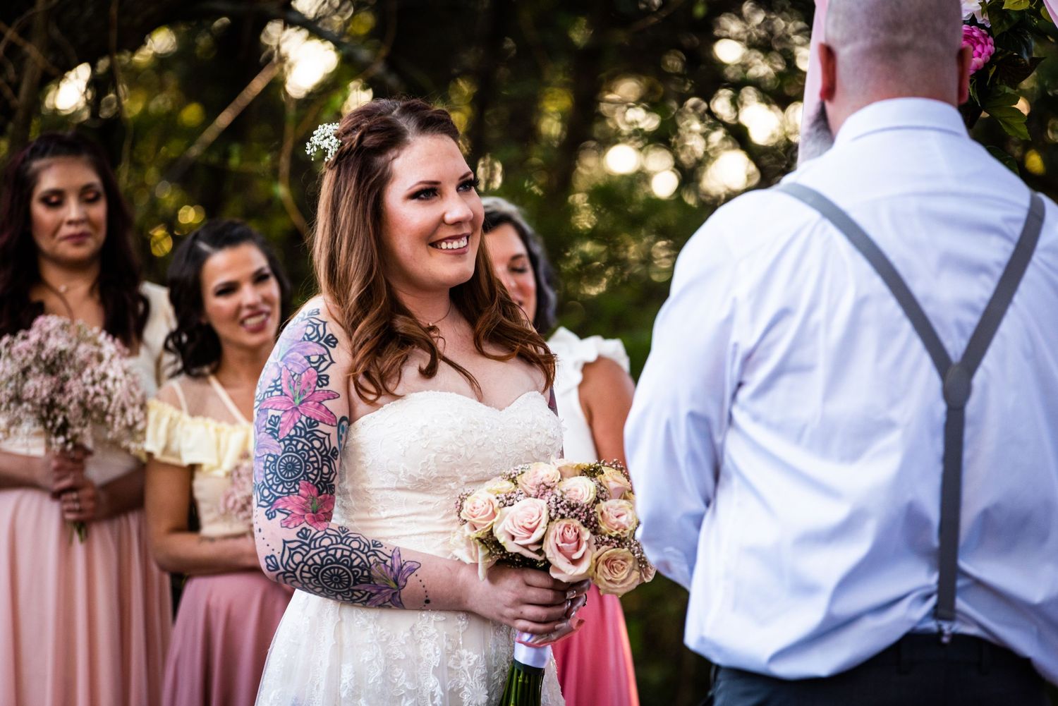 Wedding ceremony with bridal party in pink dresses and bride holding blush rose bouquet.