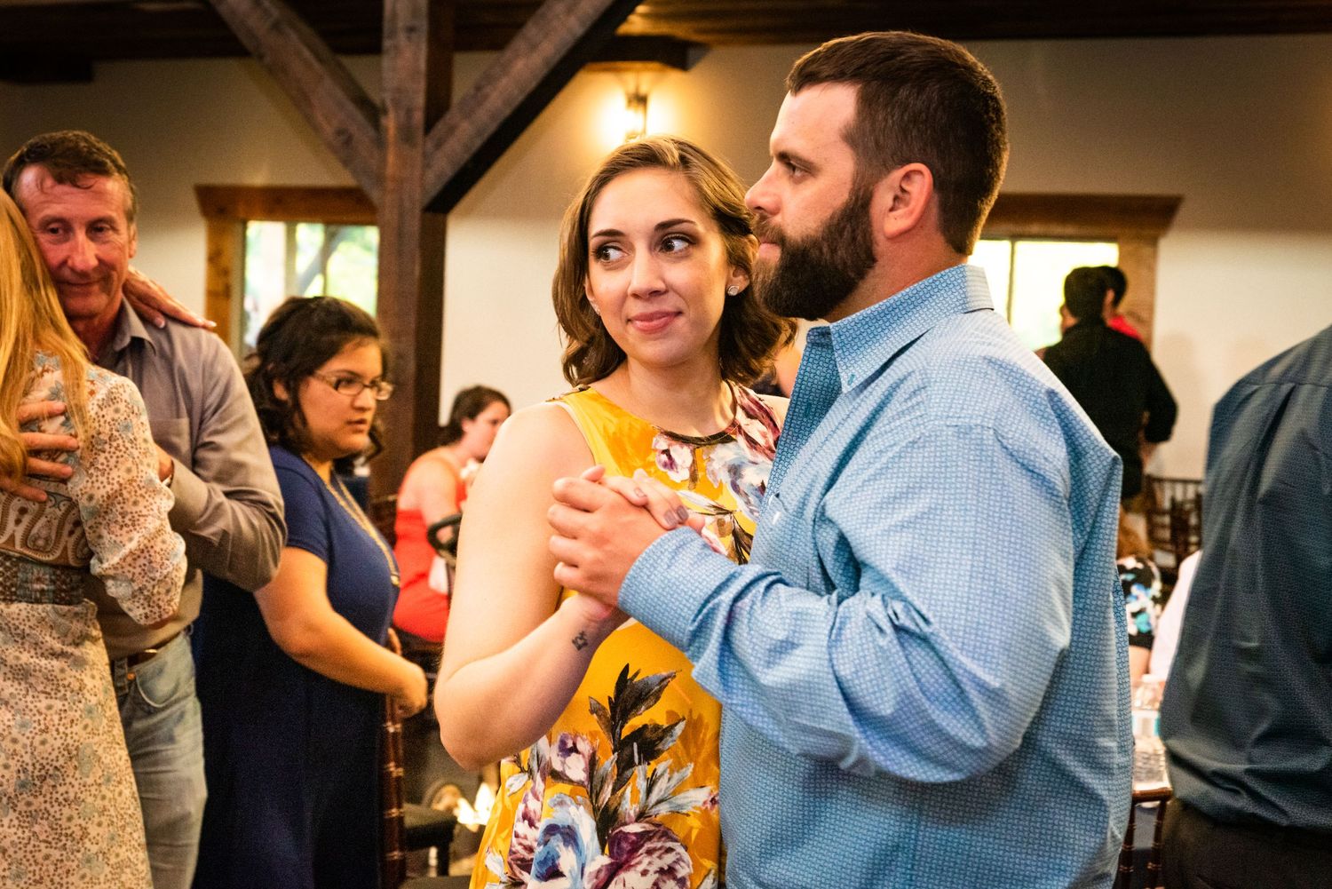 Wedding guests enjoying drinks and conversation at a rustic indoor reception venue.