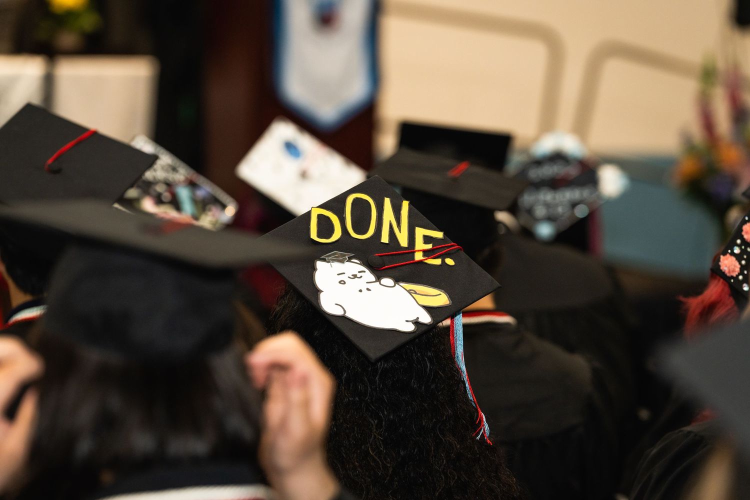 A graduation cap decorated with the word 'DONE' among a crowd of other caps.
