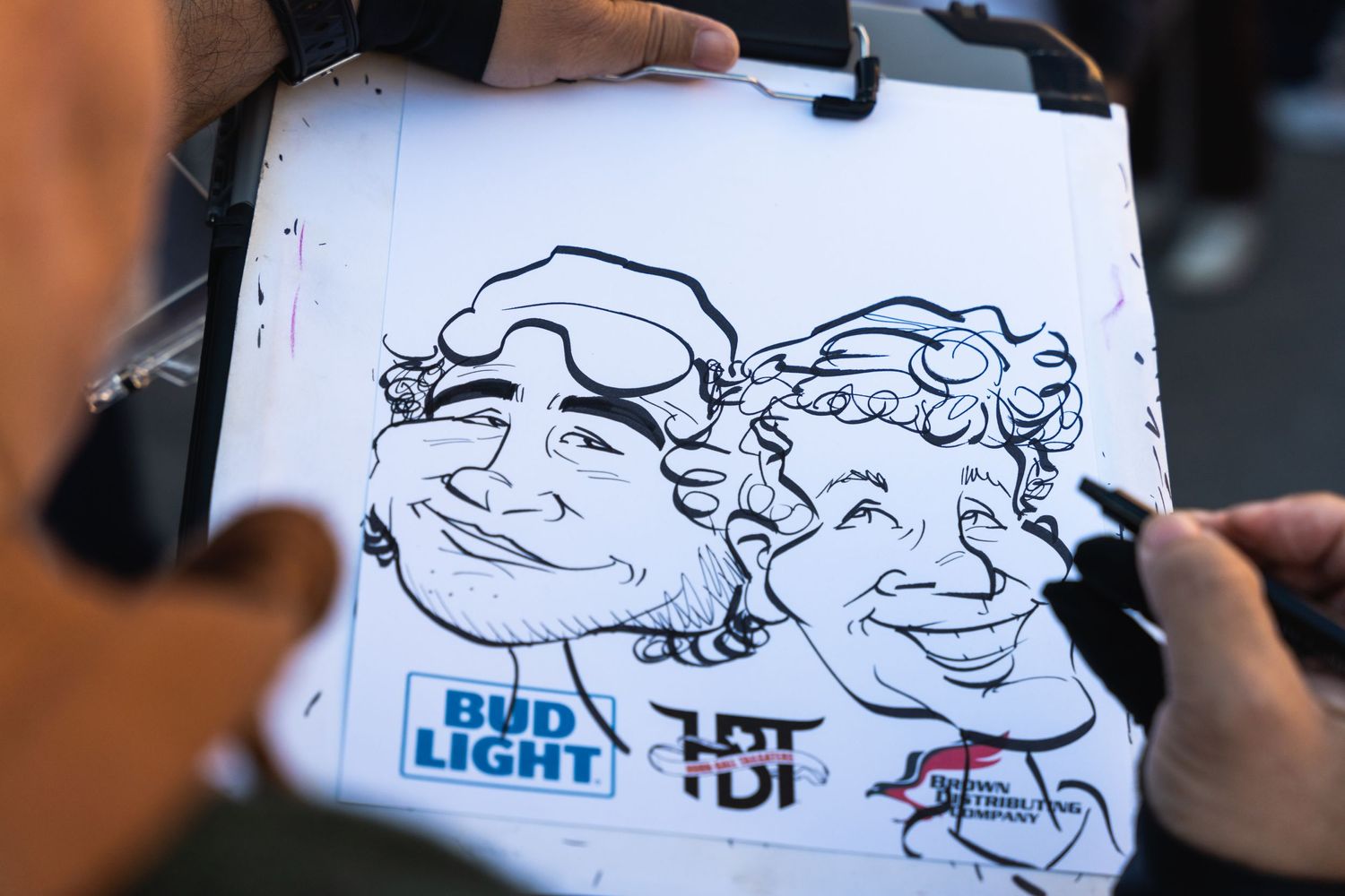 Close-up of caricature drawings being sketched on Bud Light branded paper.