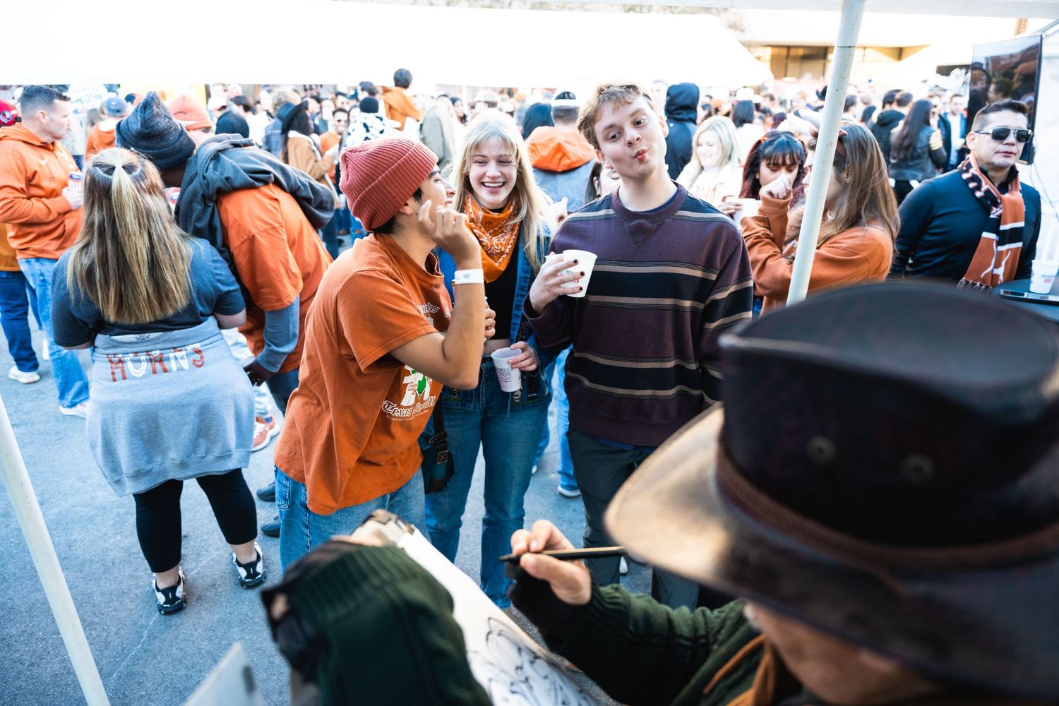 People wearing orange gather at an outdoor tailgating event.