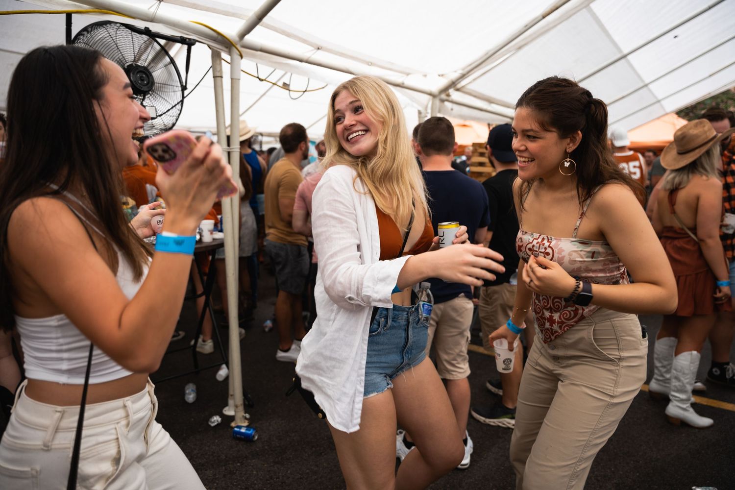 Group of friends enjoying drinks and dancing at an outdoor festival.
