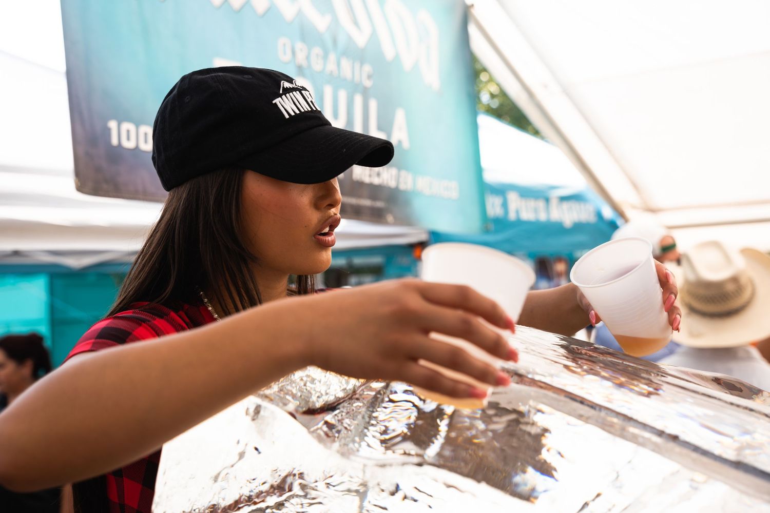 Server pours drinks at an outdoor event beverage station.