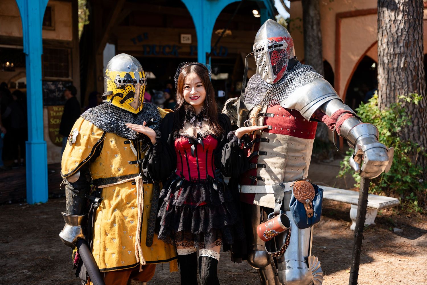 Medieval knight in full plate armor demonstrates sword fighting techniques at a historical reenactment event.