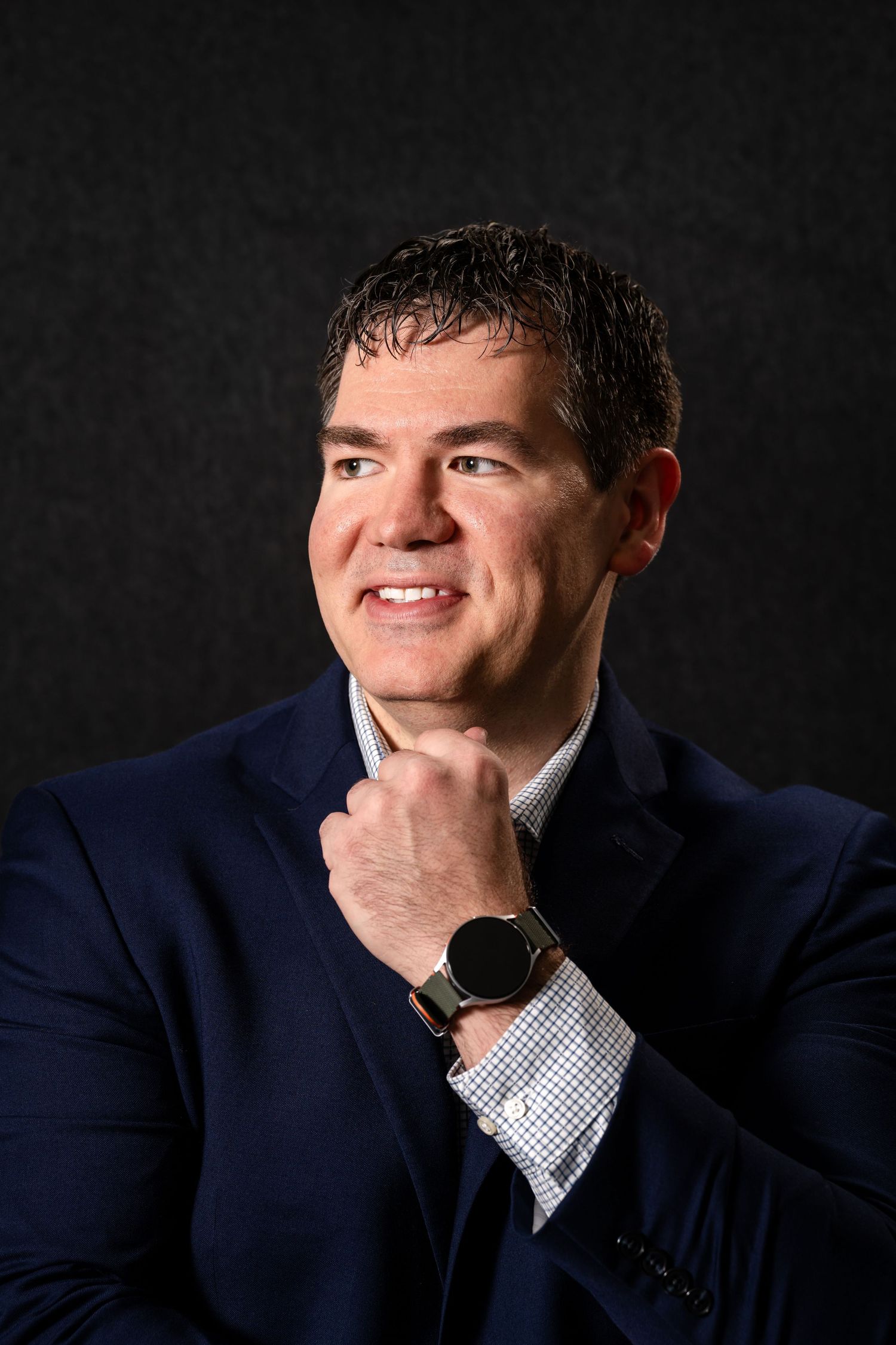 Professional headshot series against dark background showing different contemplative and friendly expressions in navy suit.