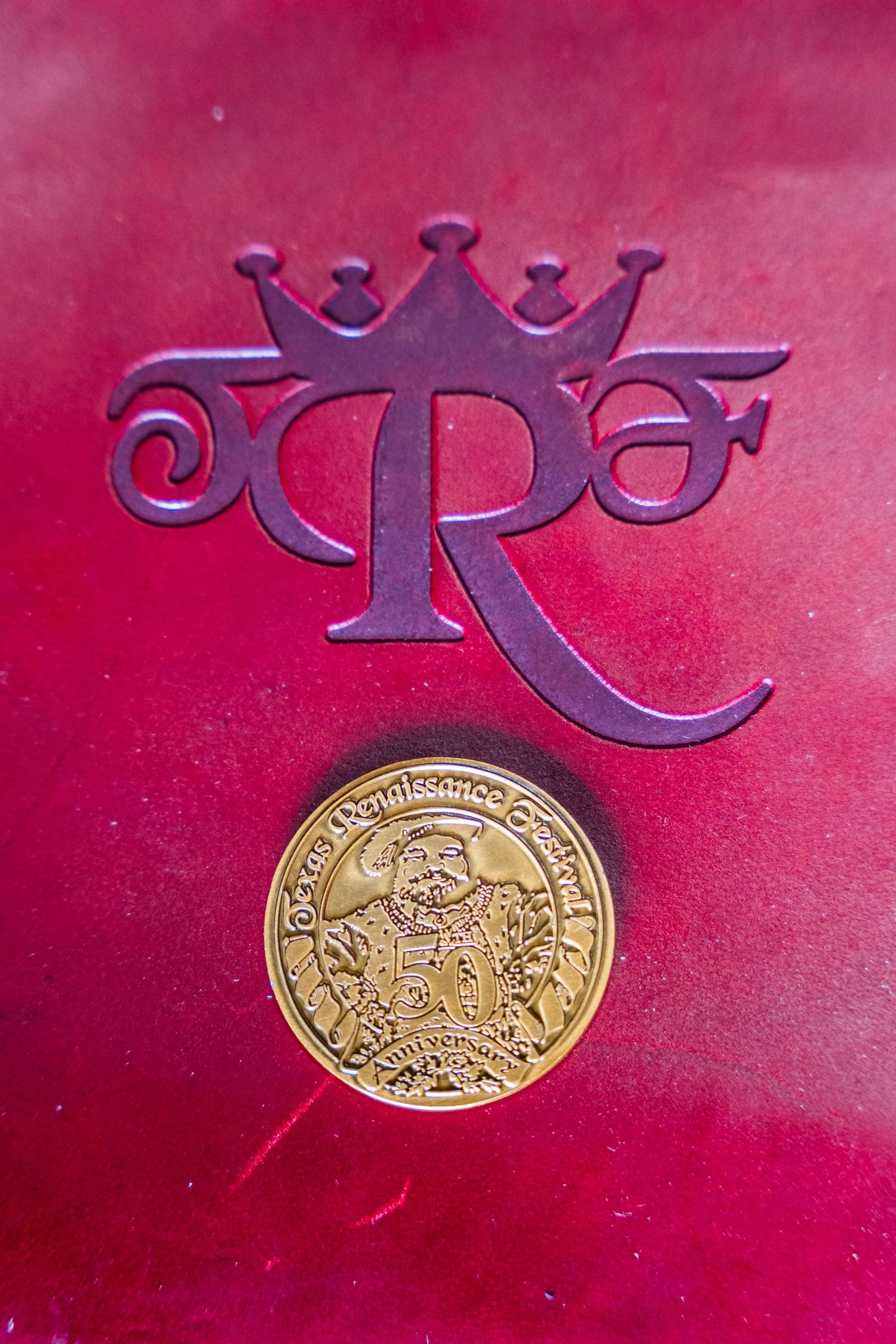 A series of decorative gold medallions and purple emblems arranged on a rich red velvet background.