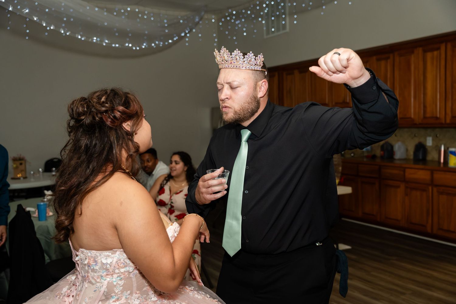 Father and daughter sharing a dance at her quinceañera, daughter in pink gown and father in black suit.
