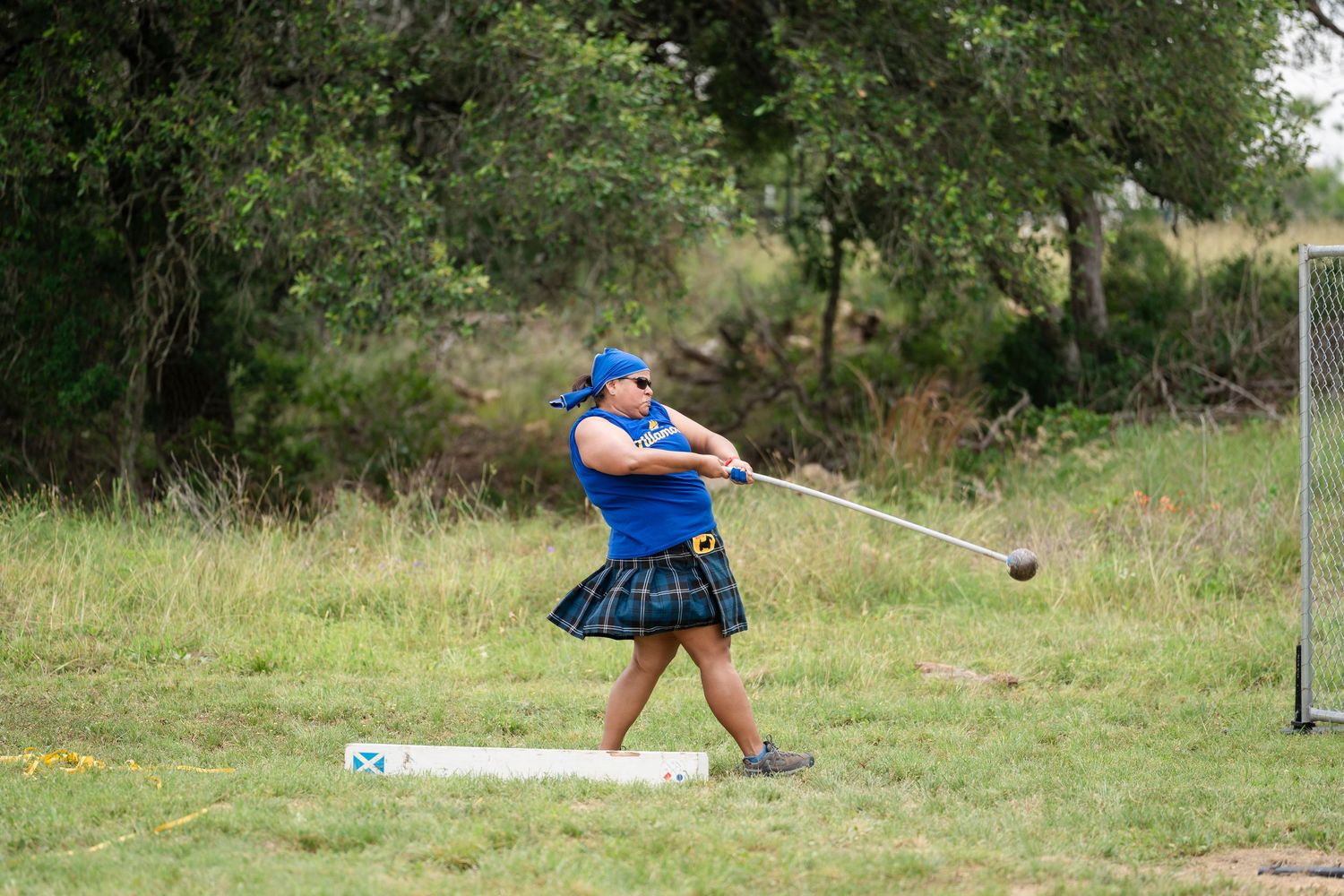 A person in blue practicing clay target shooting with a shotgun at an outdoor range.