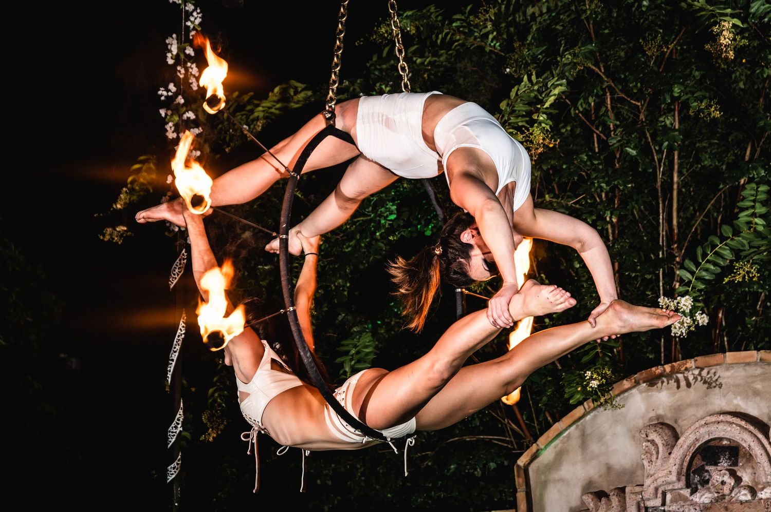 Aerial performers create circular formation during dramatic suspended nighttime performance.