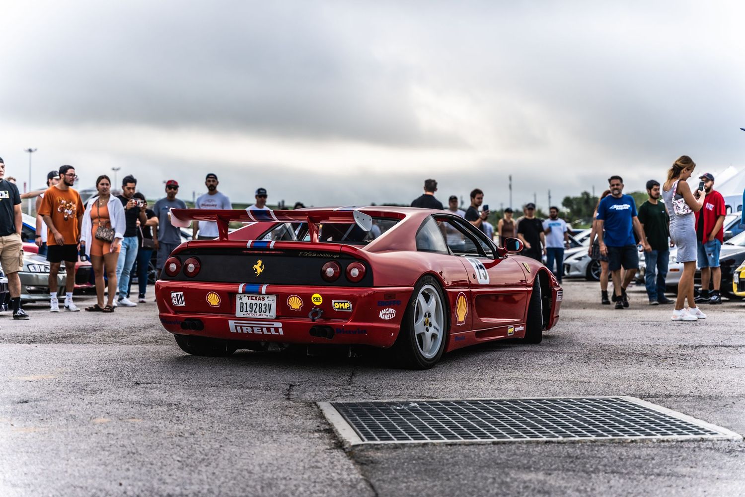 Red Ferrari F40 supercar at a car meet with spectators gathering around to admire the iconic vehicle.