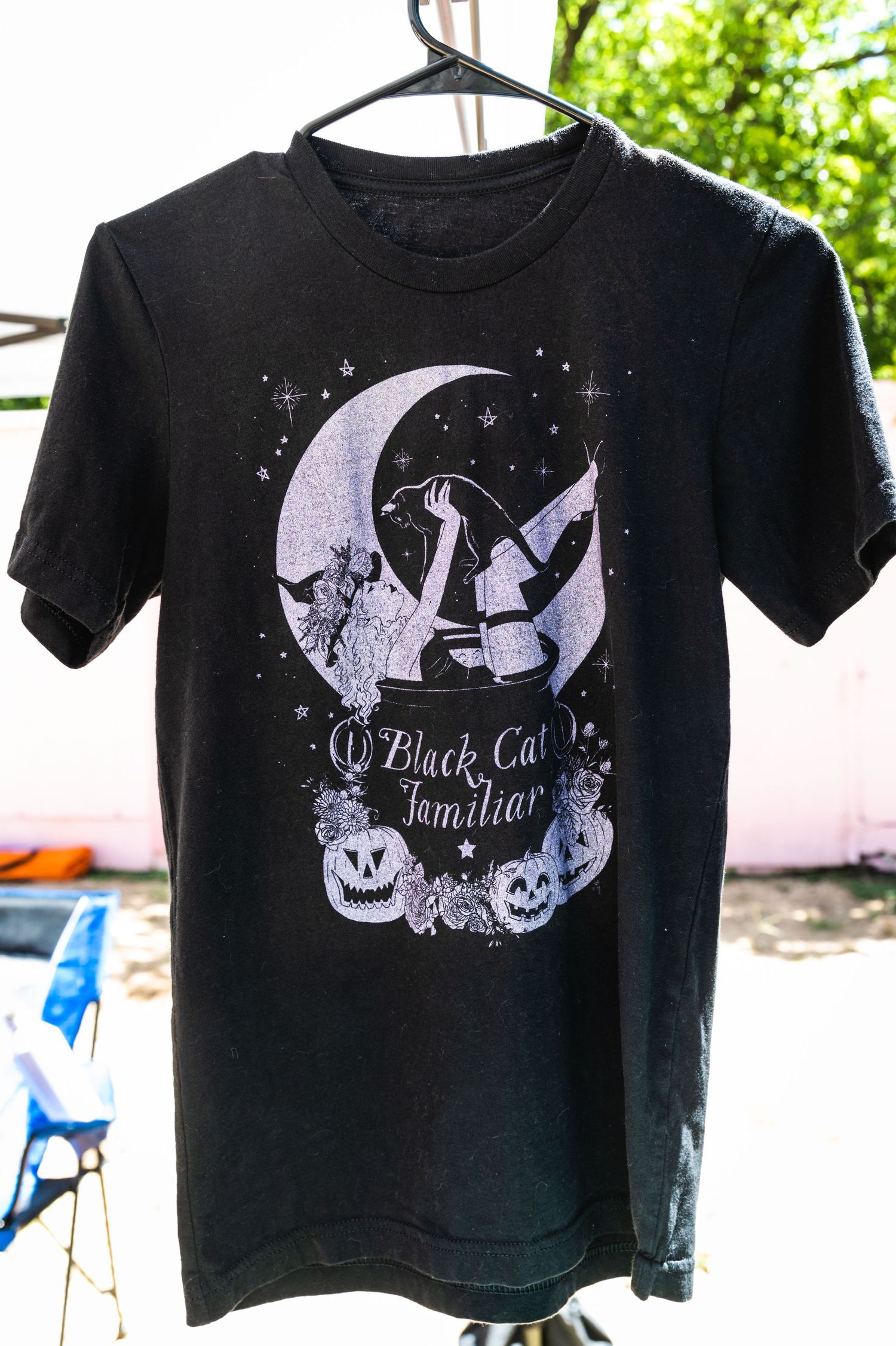 Black t-shirt with white witch-themed design featuring a moon, cats, and Halloween elements.