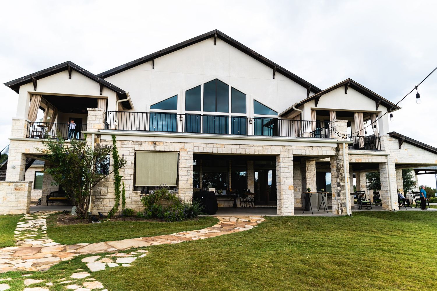 Modern white wedding venue with large windows and stone accents set on a manicured lawn.