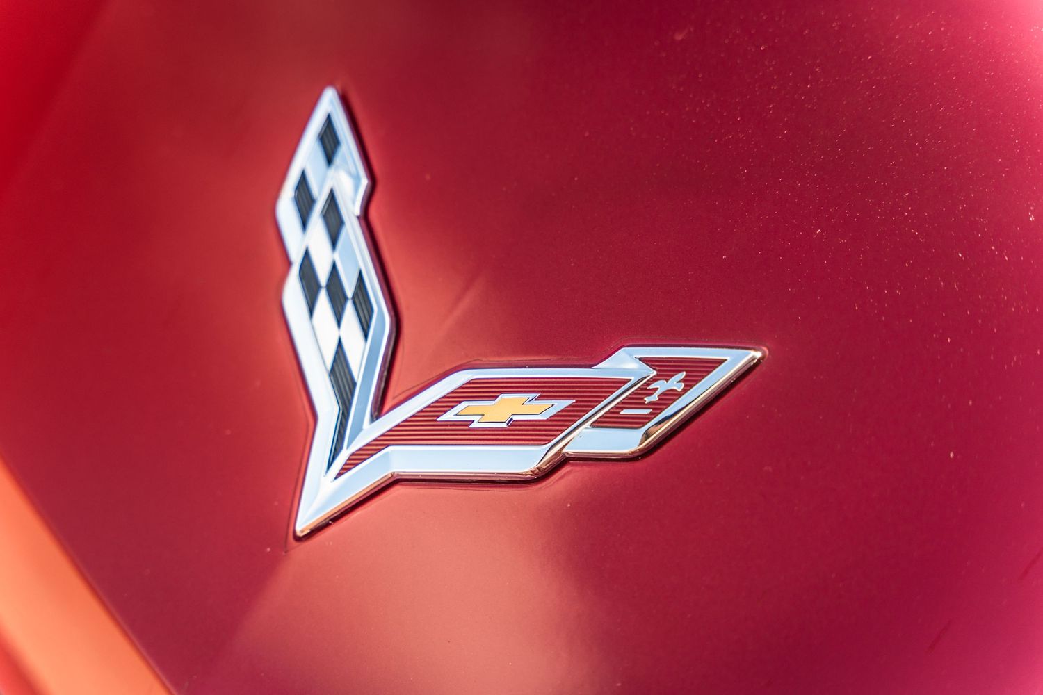 Close-up of a red Chevrolet Corvette emblem on metallic paint.