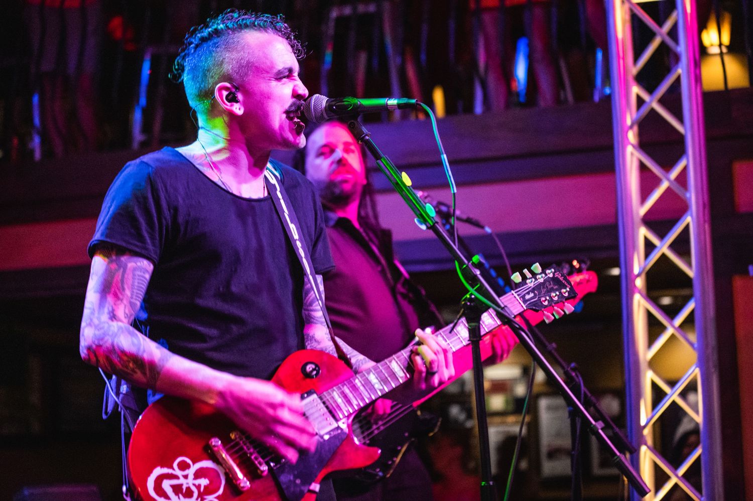 Rock musician performs with red electric guitar under dramatic stage lighting.