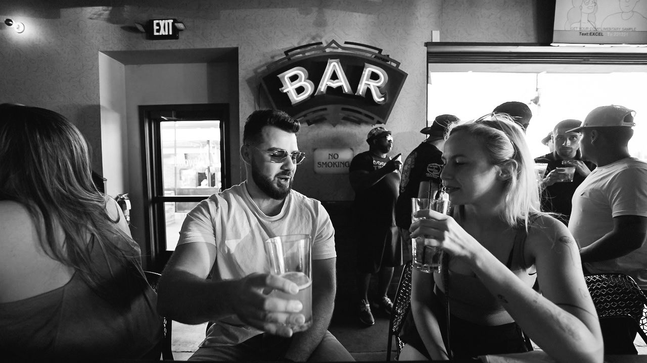Black and white photo of people socializing at a crowded bar.