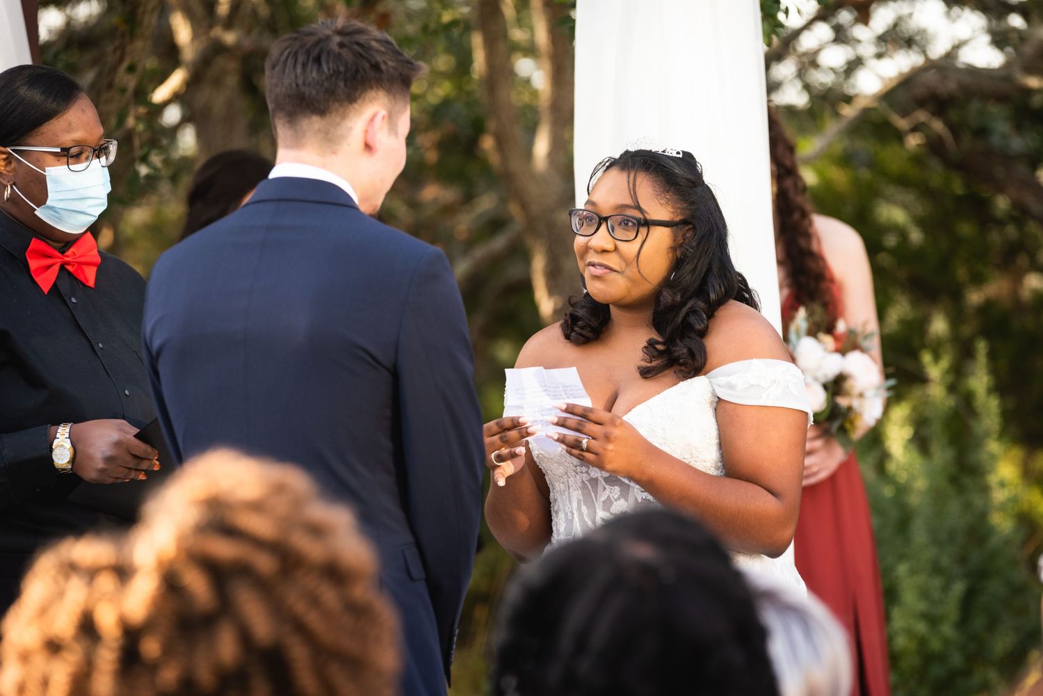 A joyful moment during the wedding ceremony as the couple exchanges vows under white draping.