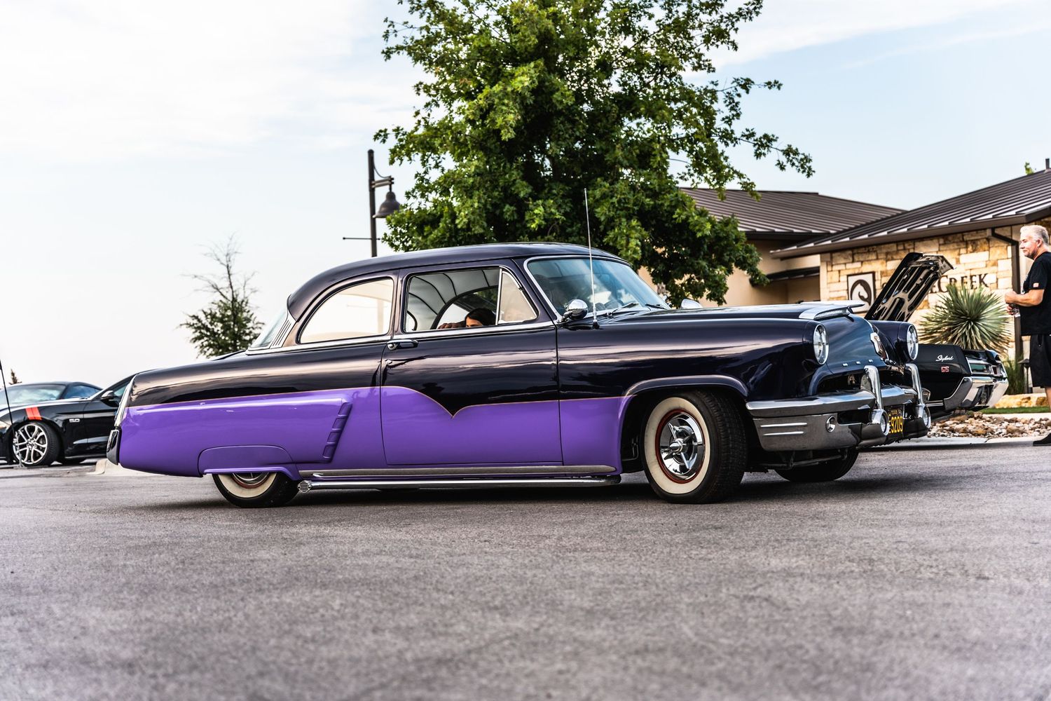 Classic purple and black two-tone vintage car with sleek chrome trim parked at a car show.