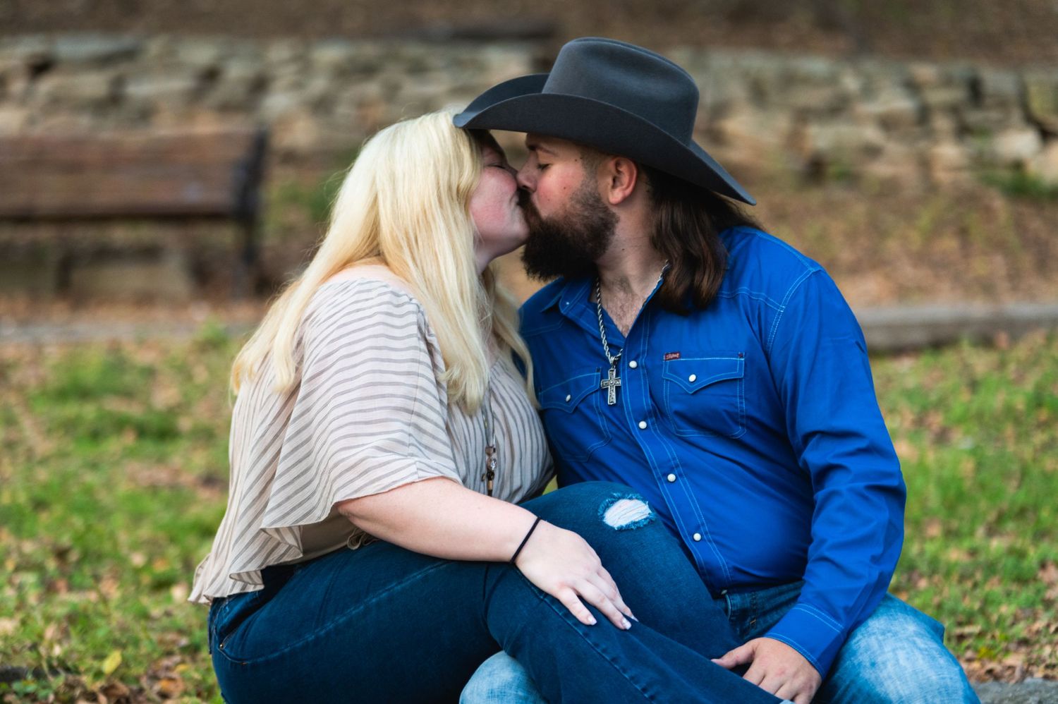 A romantic couple shares an intimate moment while sitting outdoors during a fall photo session.