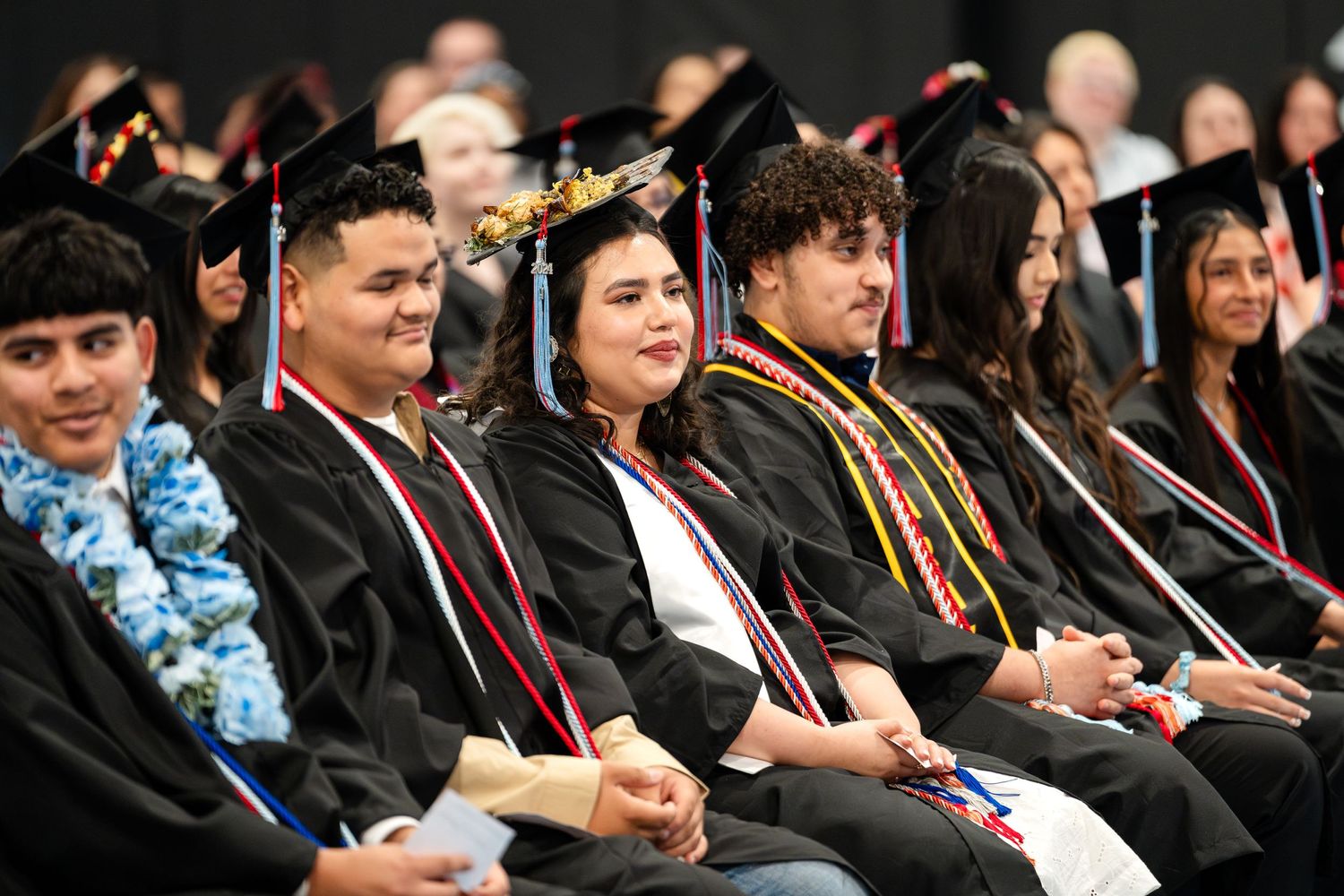 Graduates in black caps and gowns seated during commencement ceremony.