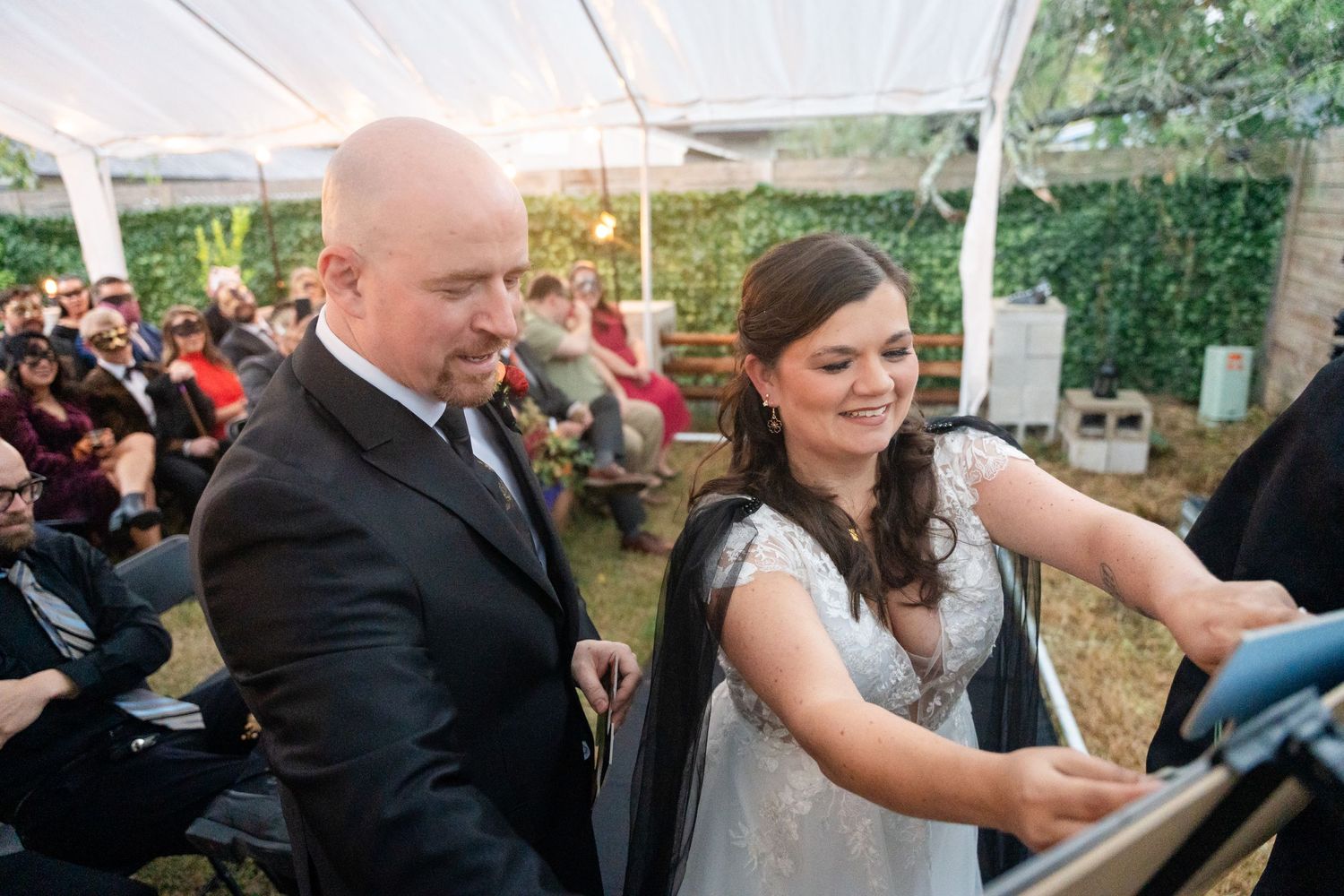 Couple participating in wedding ceremony activities under white tent.