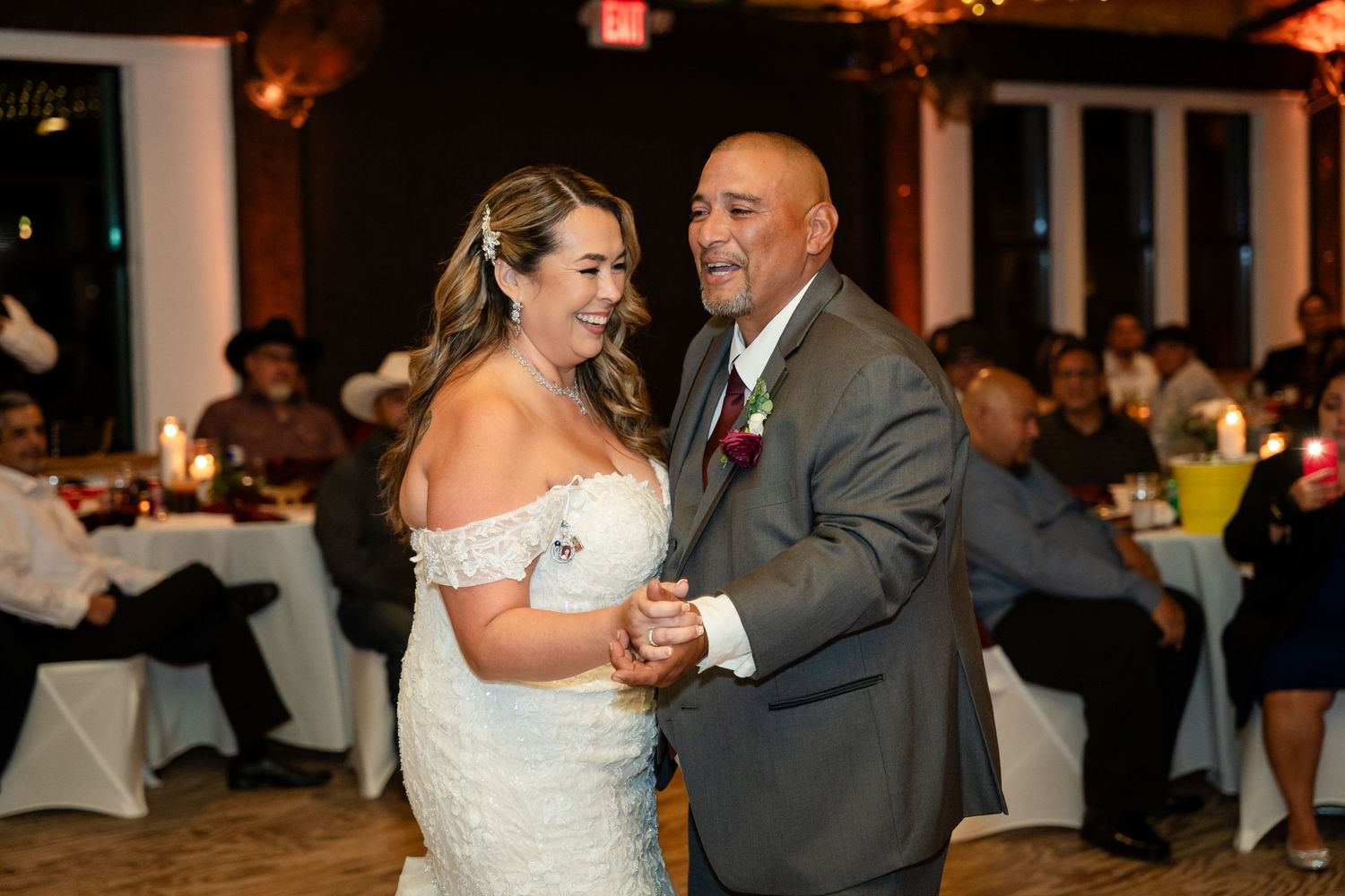A couple shares a romantic dance moment during their wedding reception in an elegantly lit venue.