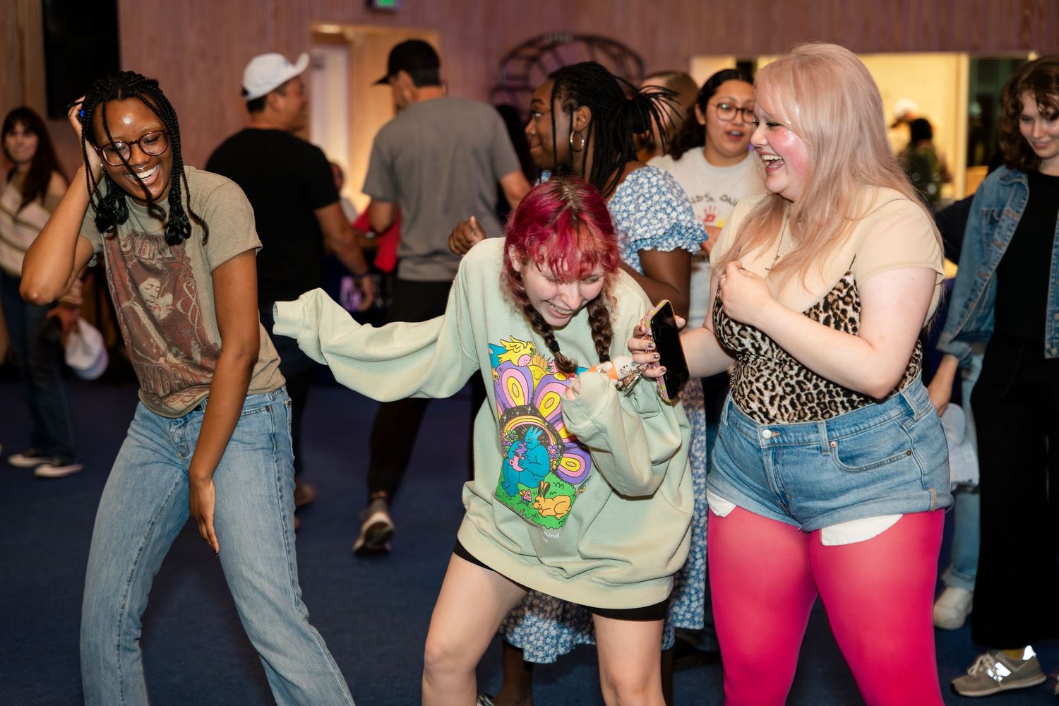 People dancing and moving enthusiastically at what appears to be a casual indoor party or dance event.