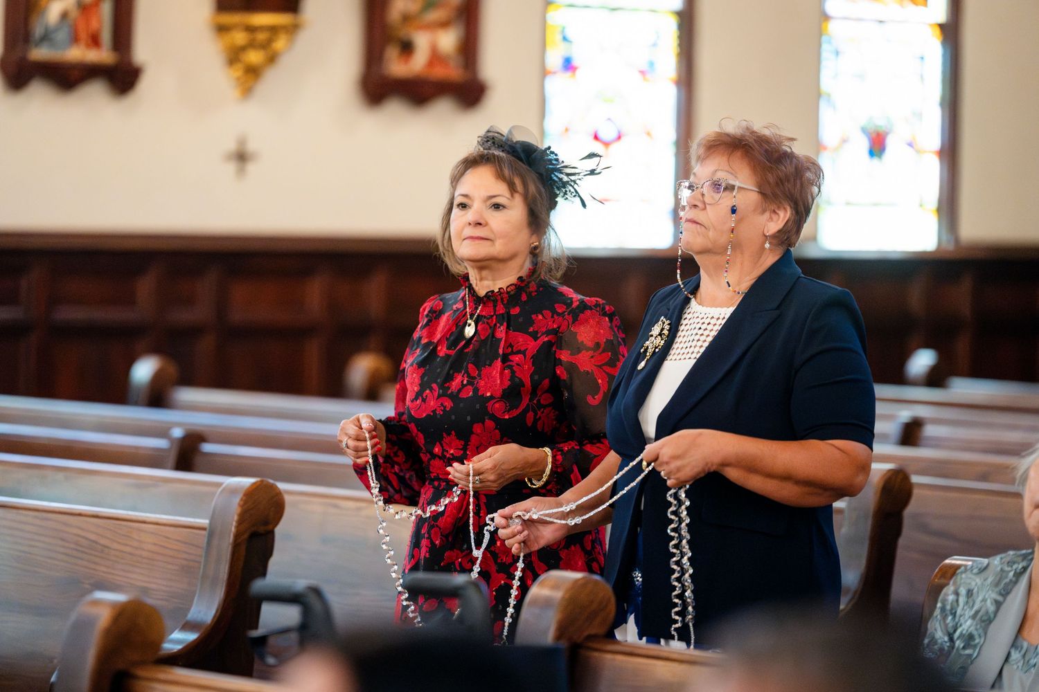 Two people stand in church pews holding hymnals during a worship service.