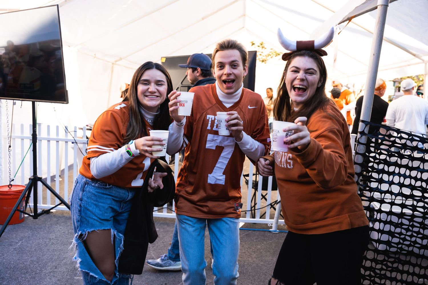 Friends in Texas Longhorns gear celebrate together at a tailgating event.
