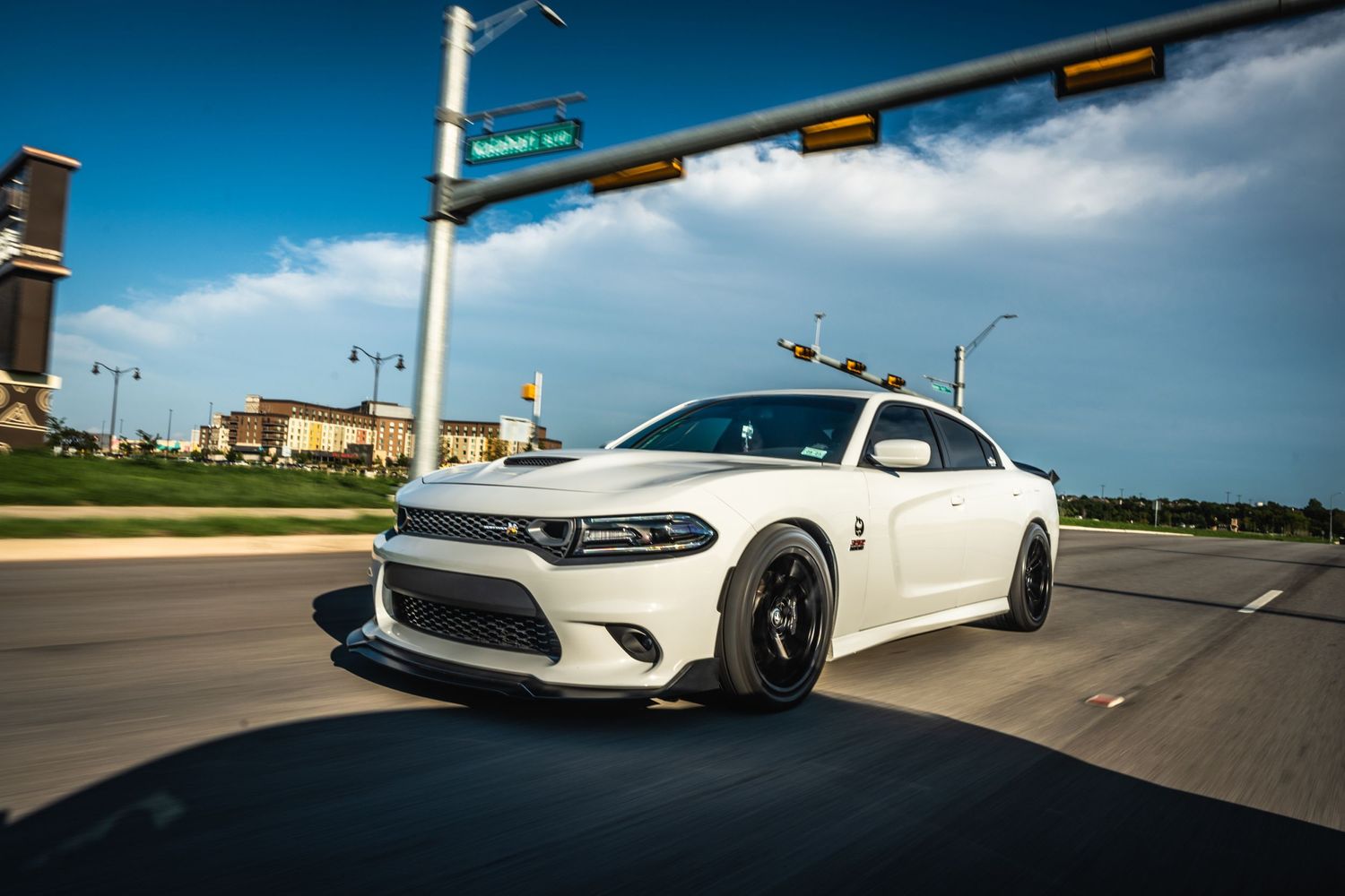 Modified white Dodge Charger with black wheels photographed at street intersection.