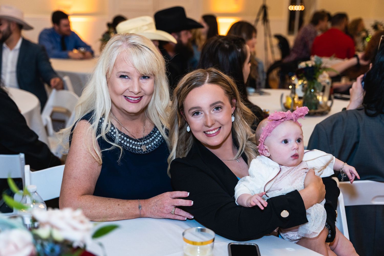Three generations gather for a candid moment at a wedding reception.