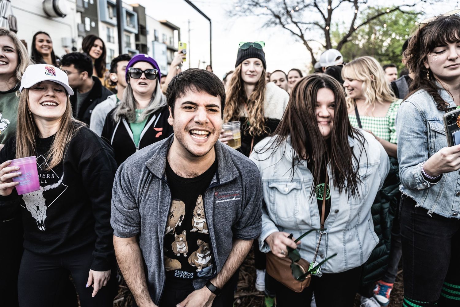 Lively crowd of concertgoers with colorful drinks enjoying an outdoor music event.