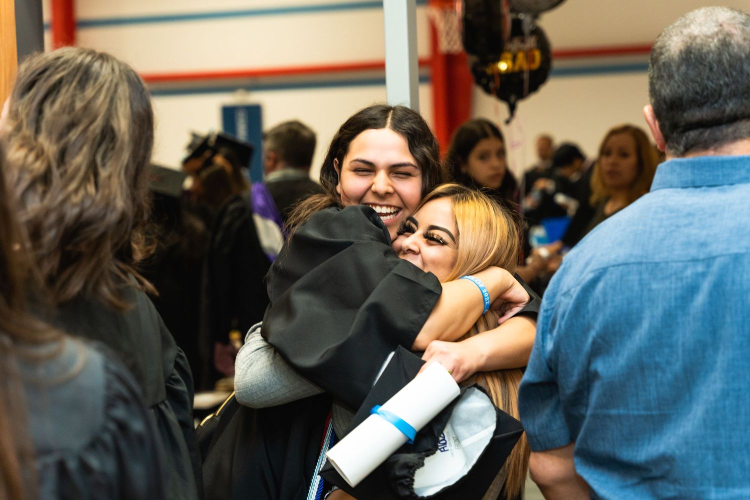 Friends share joyful hugs during a crowded celebration event.