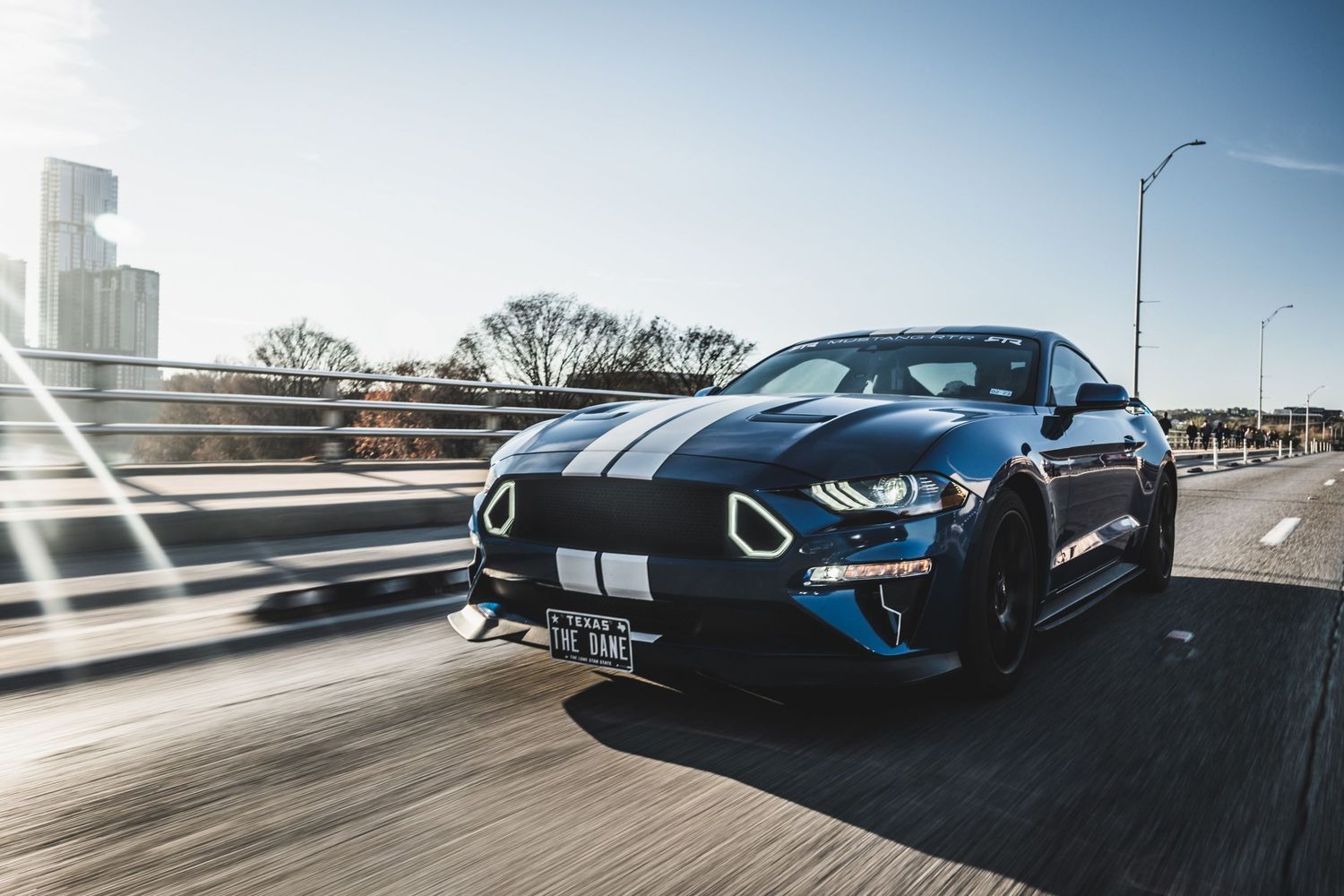 Front view of a black Ford Mustang GT with racing stripes captured in dynamic motion.