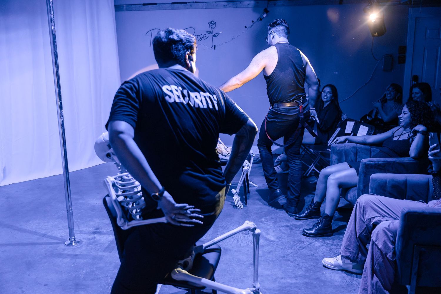 Security guard watches performance in blue-lit theater space.