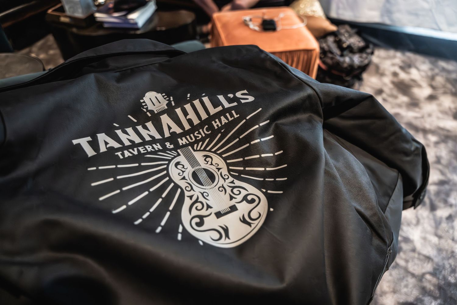 Black jacket with Tannahill's logo featuring stylized guitar design in white print.