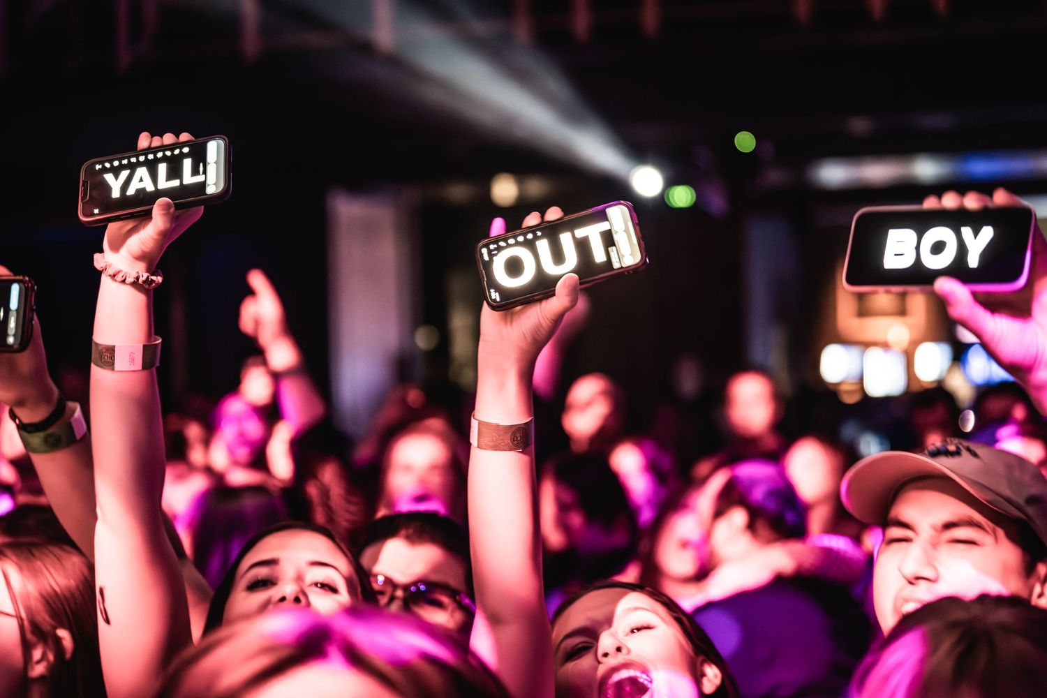 Concert fans hold up illuminated signs spelling 'YALL OUT BOY' during performance.