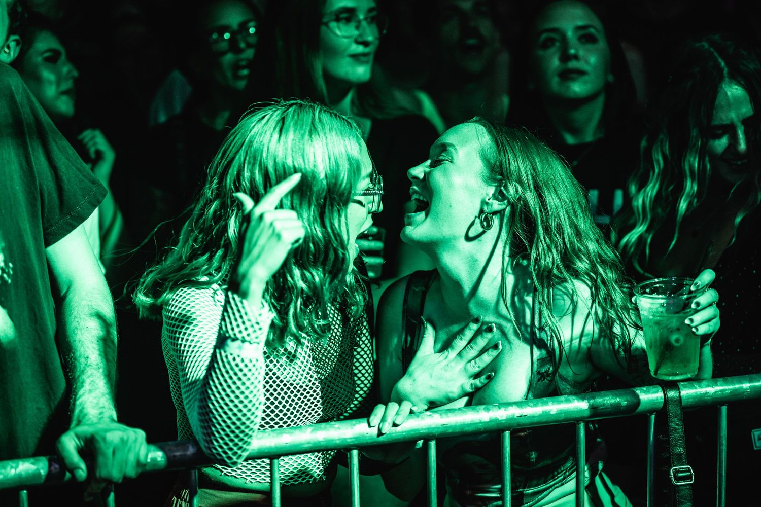 Concert attendees enjoying show with dramatic green lighting effects.