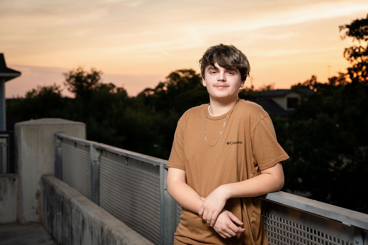Someone in casual attire poses on rooftop during golden hour sunset.
