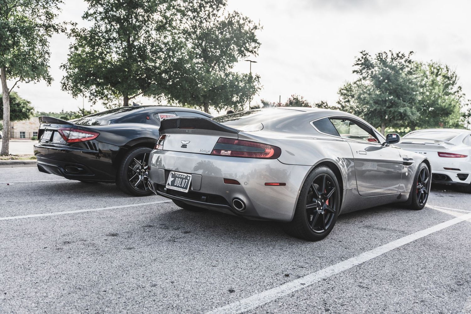 Modern Aston Martin sports cars in black and silver parked side by side.