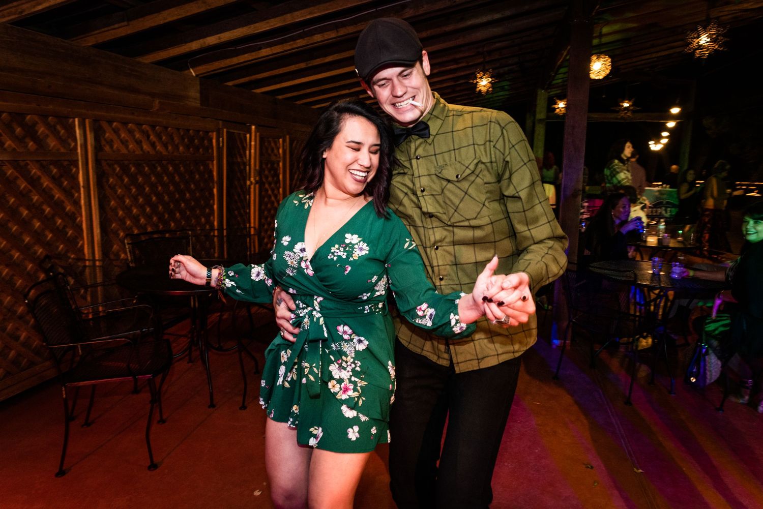 Couple having fun dancing together at evening reception with colorful lights.