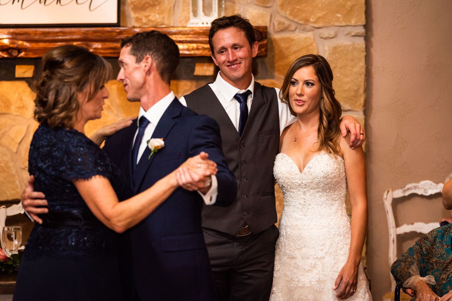 A touching moment during a wedding reception in a rustic stone-walled venue.