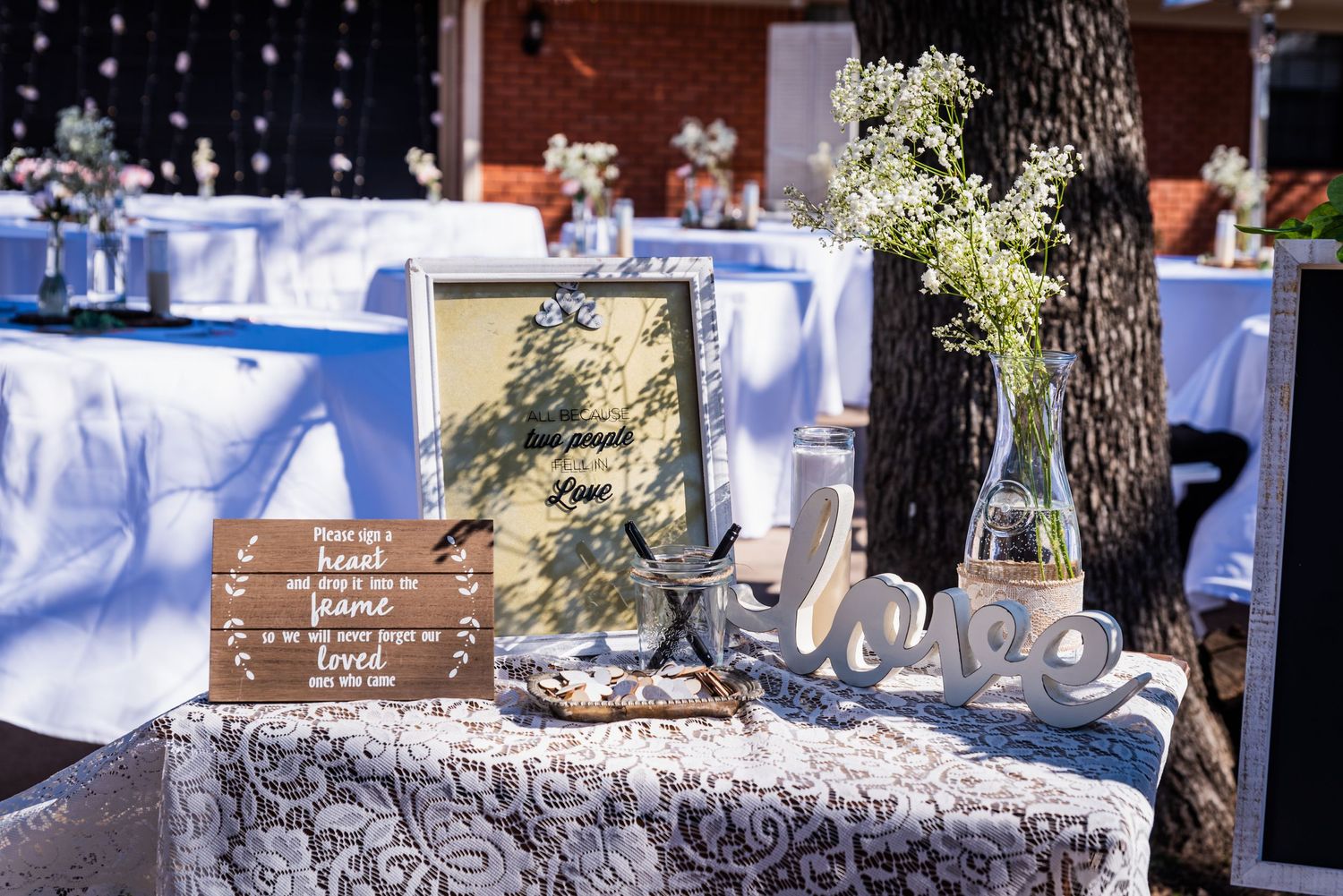 Rustic wedding decor featuring wooden sign and table settings with blue tablecloths.