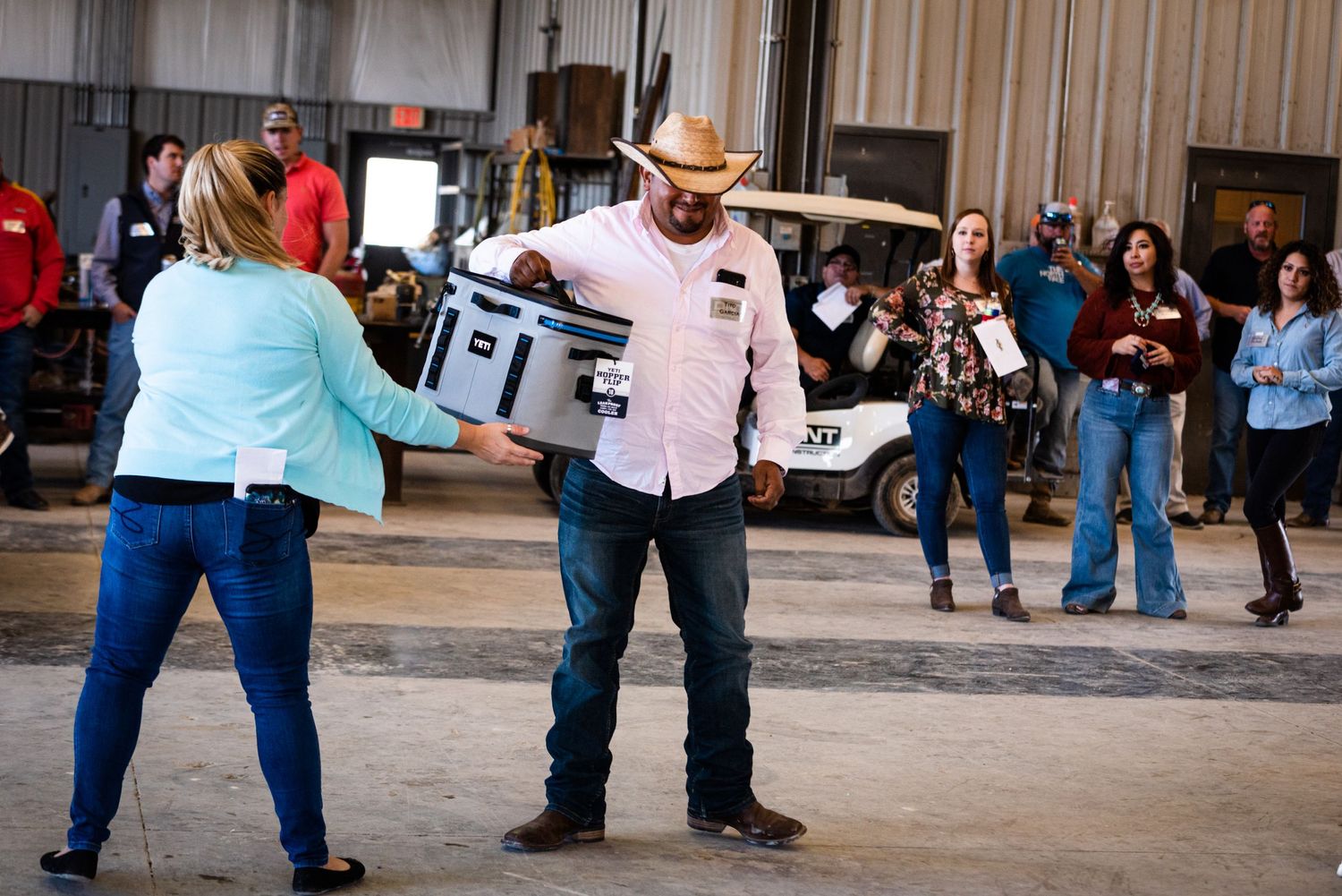 Two people handling YETI cooler during indoor event.
