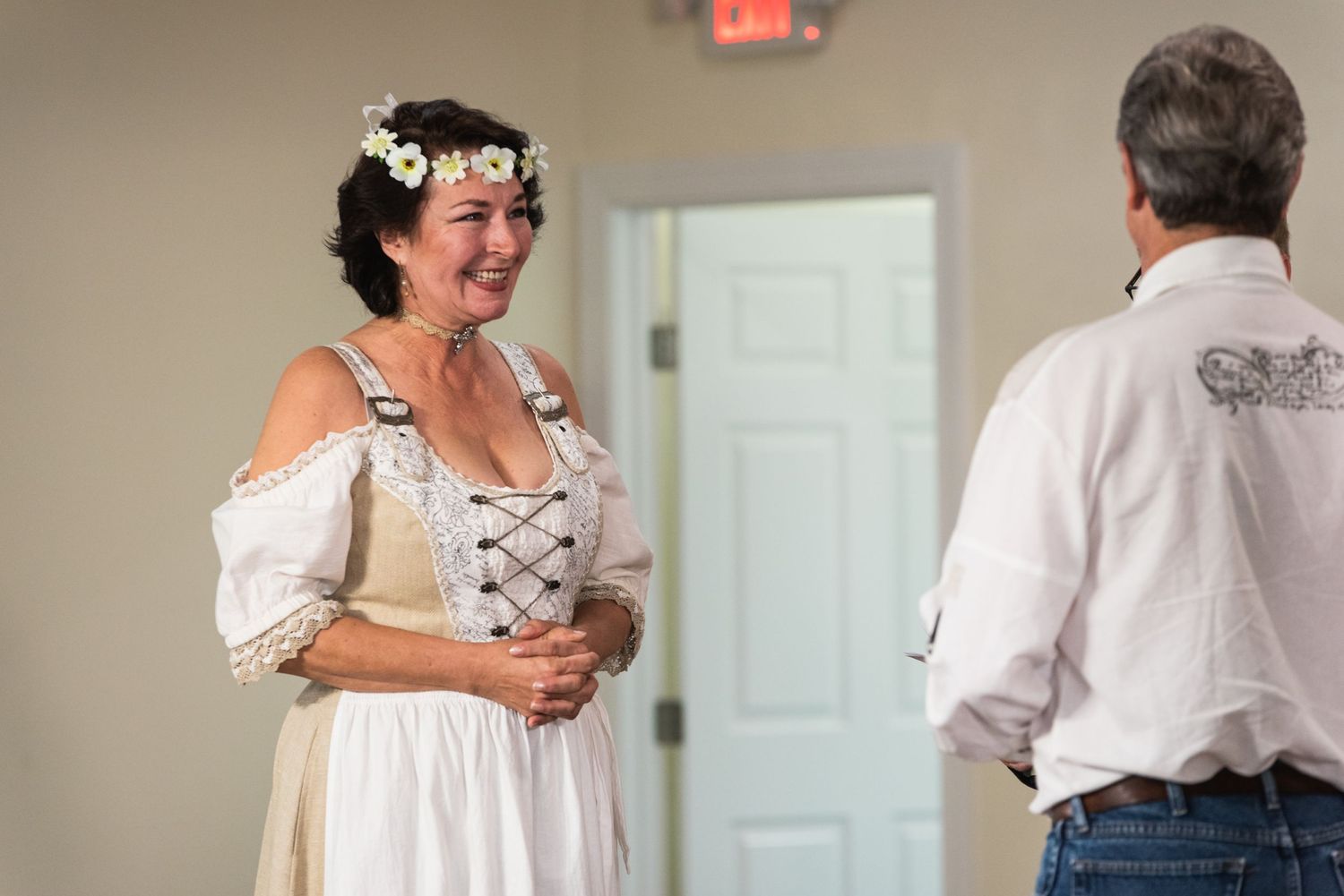 Person in white dress with flower crown smiling during ceremony.