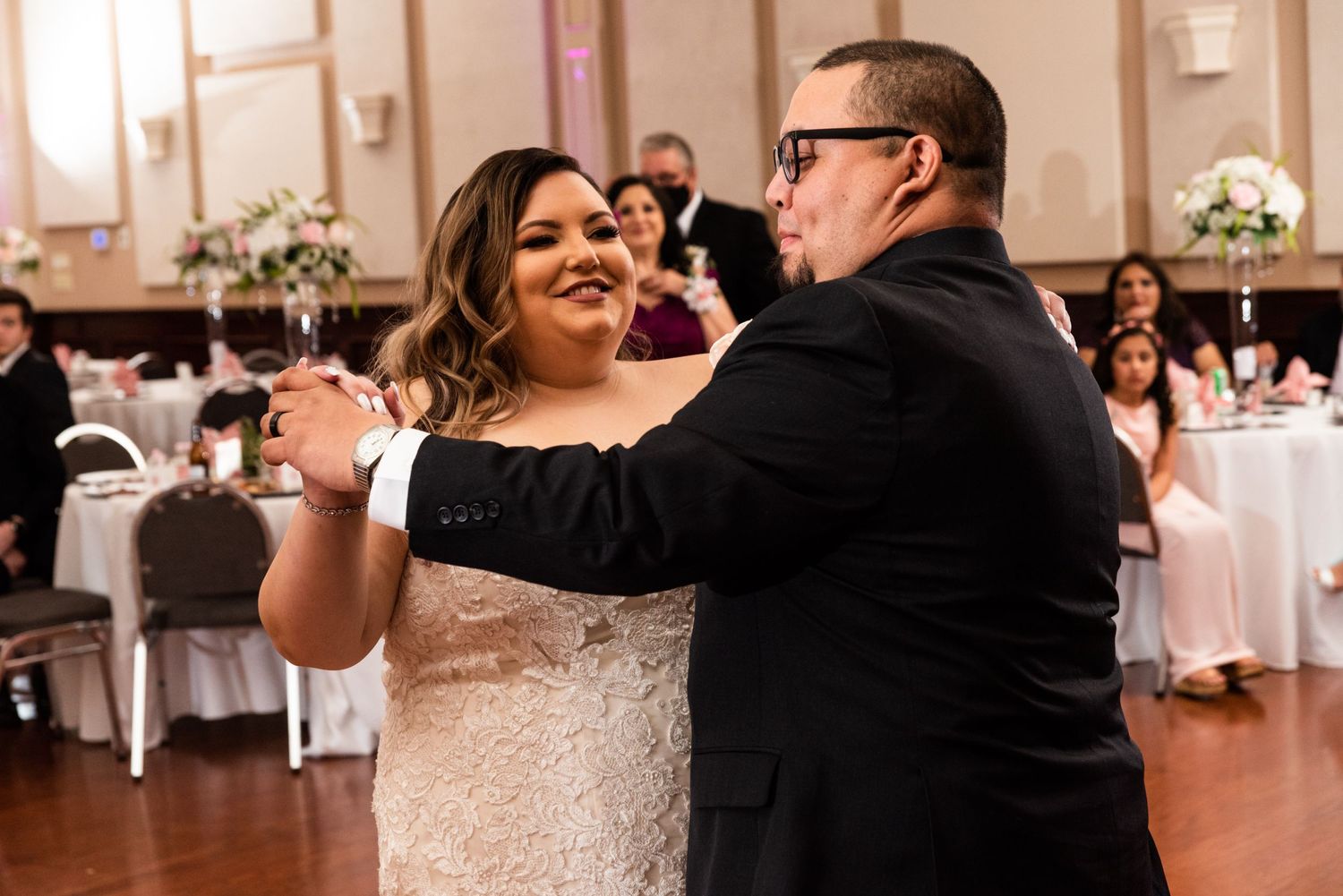 A couple dancing together at a wedding reception in formal attire.