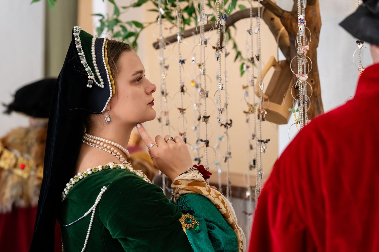 Two people in medieval renaissance costumes dance together at a festive celebration with string lights in the background.